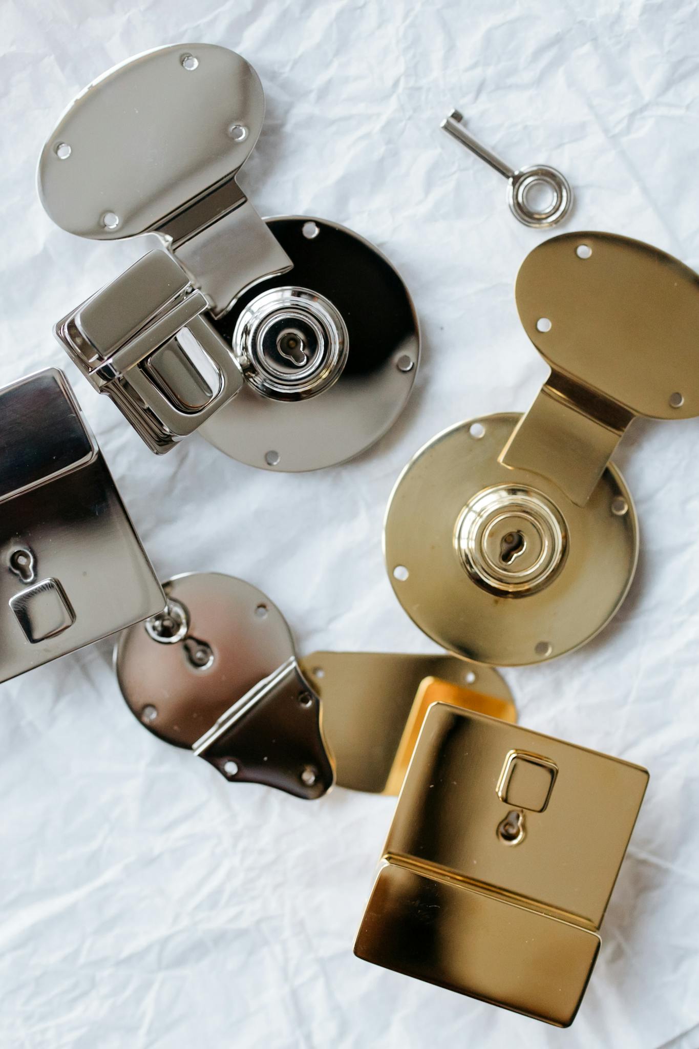 A curated flatlay showcasing chrome and brass locks on a textured white background.