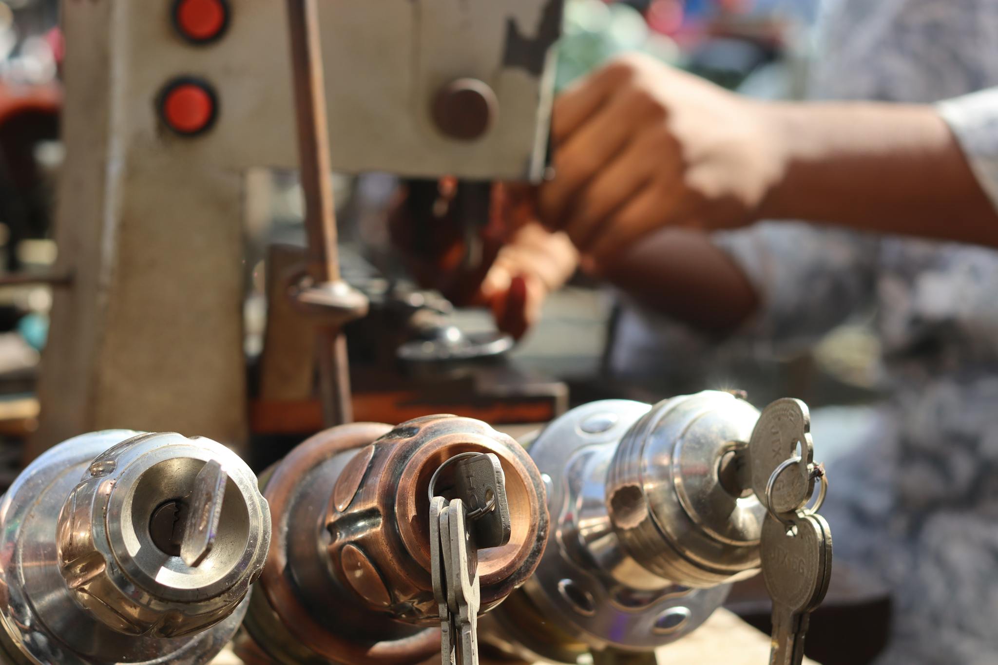 Close-up image of locksmith tools and hands working with a key machine outdoors.